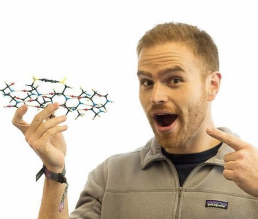 Anthony Rojas holding a molecular model and smiling
