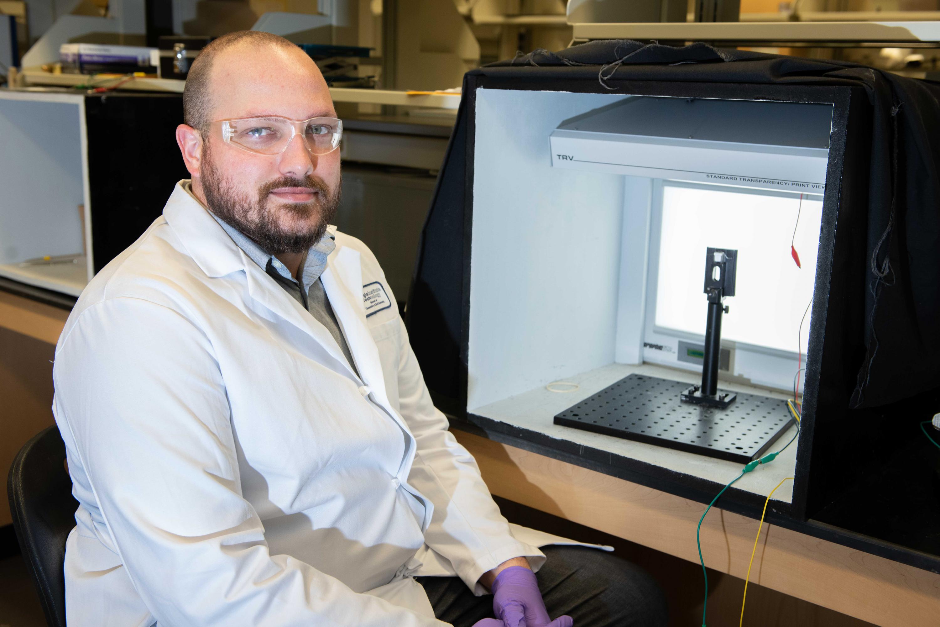 Graduate Research Assistant Dylan Christiansen is shown with a transparent electrochemical cell that allows examination of materials color change upon application of an oxidizing voltage. (Photo: Allison Carter, Georgia Tech)