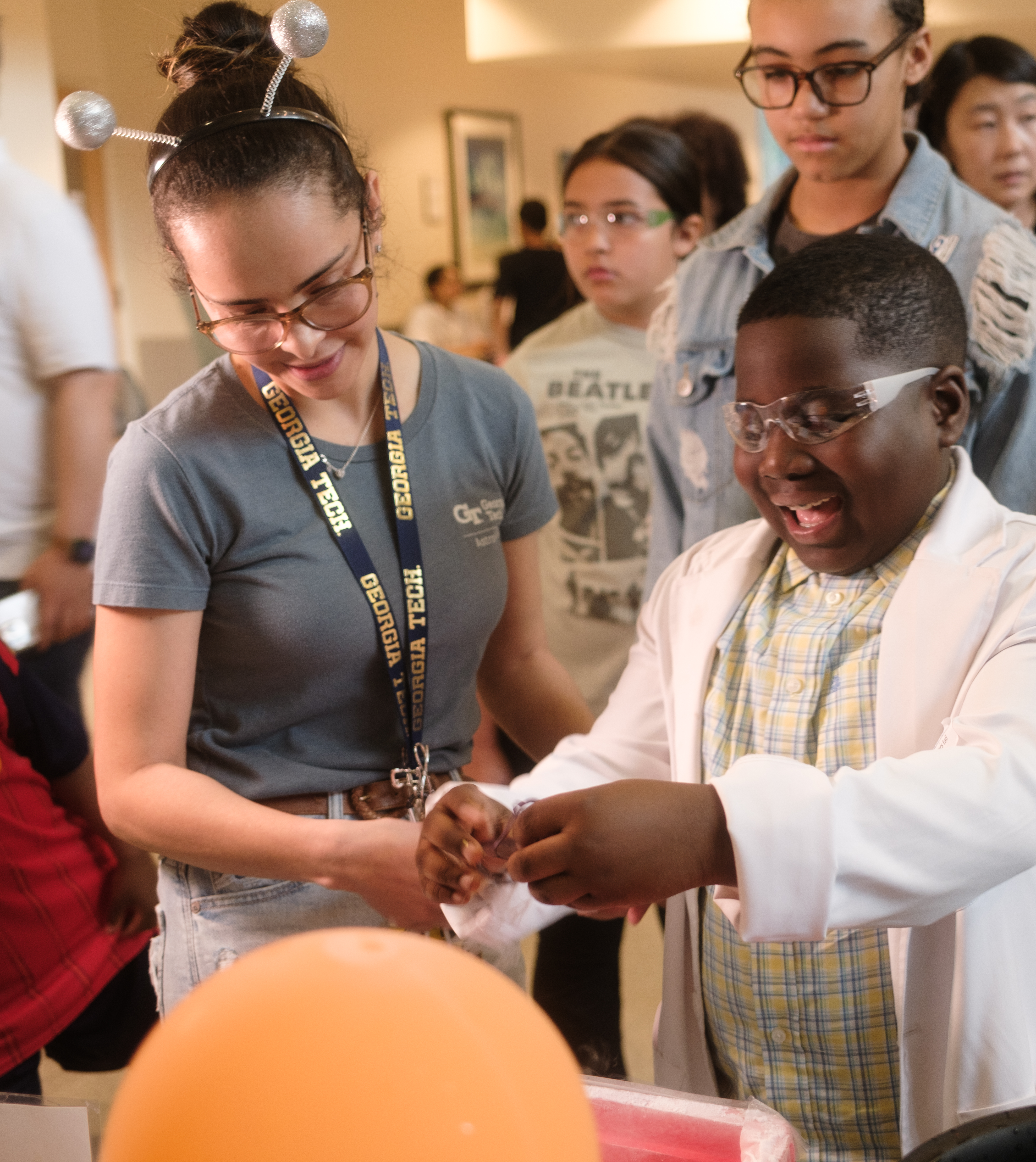 A young student in a lab coat works with an older graduate student.