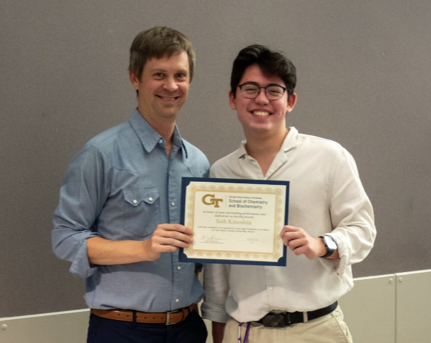 Two people holding an award certificate.