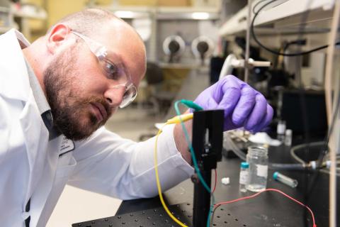 Graduate Research Assistant Dylan Christiansen studies the electrochromic properties of new materials in a transparent electrochemical cell that allows examination of color change upon application of an oxidizing voltage. (Photo: Allison Carter, Georgia Tech)